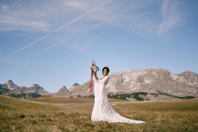 Woman with umbrella on field against sky