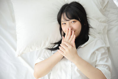 Portrait of young woman sitting on bed at home