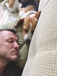 Close-up of mid adult man with dog sleeping on bed at home