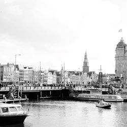 Sailboats moored on river against buildings in city