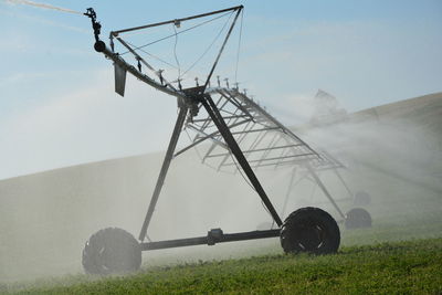 Sprinkler on field against sky