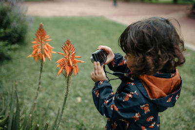 Cute girl photographing plant outdoors