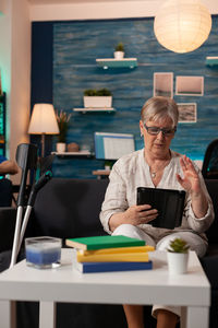 Senior woman talking on digital tablet at home office