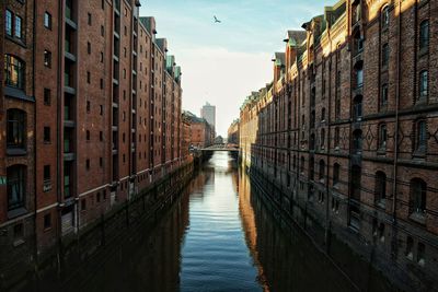 Canal amidst buildings in city against sky