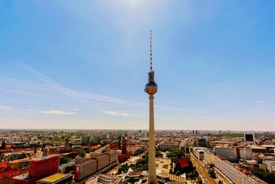 Communications tower in city against sky