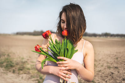 Young woman holding tulips while standing on field