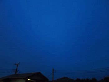 Low angle view of silhouette roof against blue sky