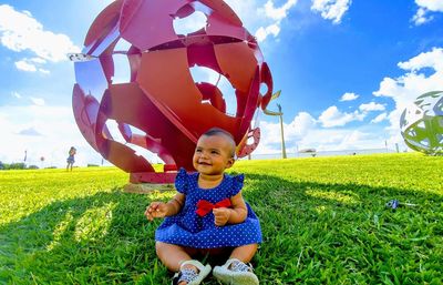 Portrait of cute boy sitting on field against sky