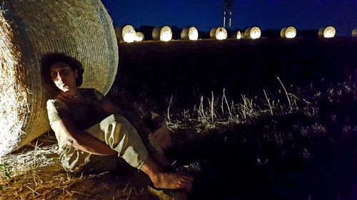 Side view of man sitting on field at night