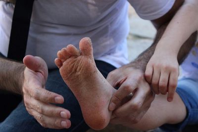 Midsection of man cleaning daughter dirty foot