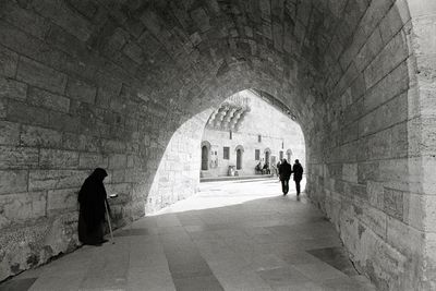 Rear view of people walking in tunnel