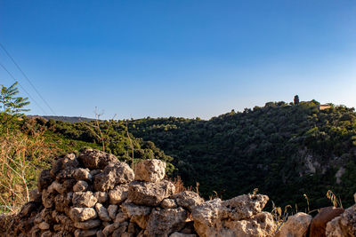 Rocks on landscape against clear blue sky