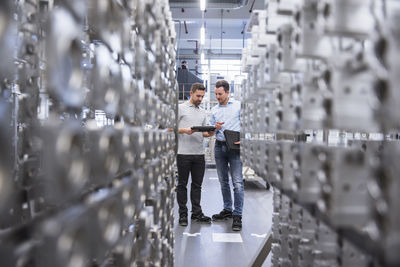 Two men with tablet talking in factory shop floor