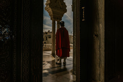 Rear view of man standing against door of building