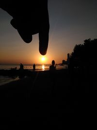 Silhouette man on beach against clear sky during sunset