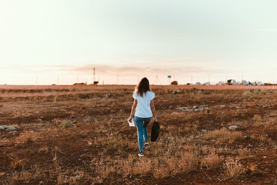 Rear view of woman walking on field