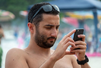 Portrait of young man using mobile phone on the beach