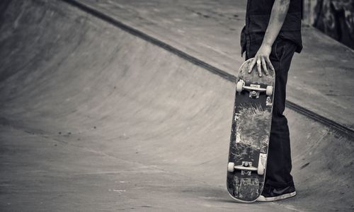 Low section of man standing with skateboard on sports ramp