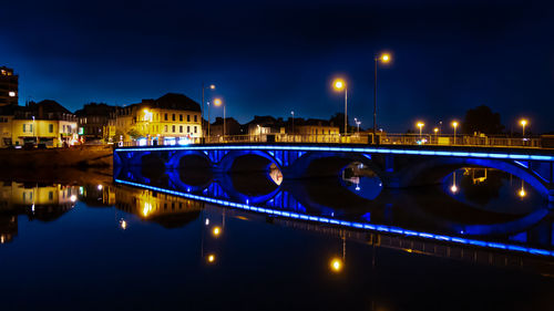 Illuminated bridge over river against sky in city at night