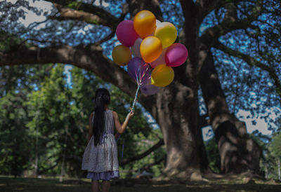 Rear view of woman holding colorful balloons