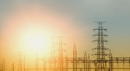 Low angle view of electricity pylon against sky during sunset