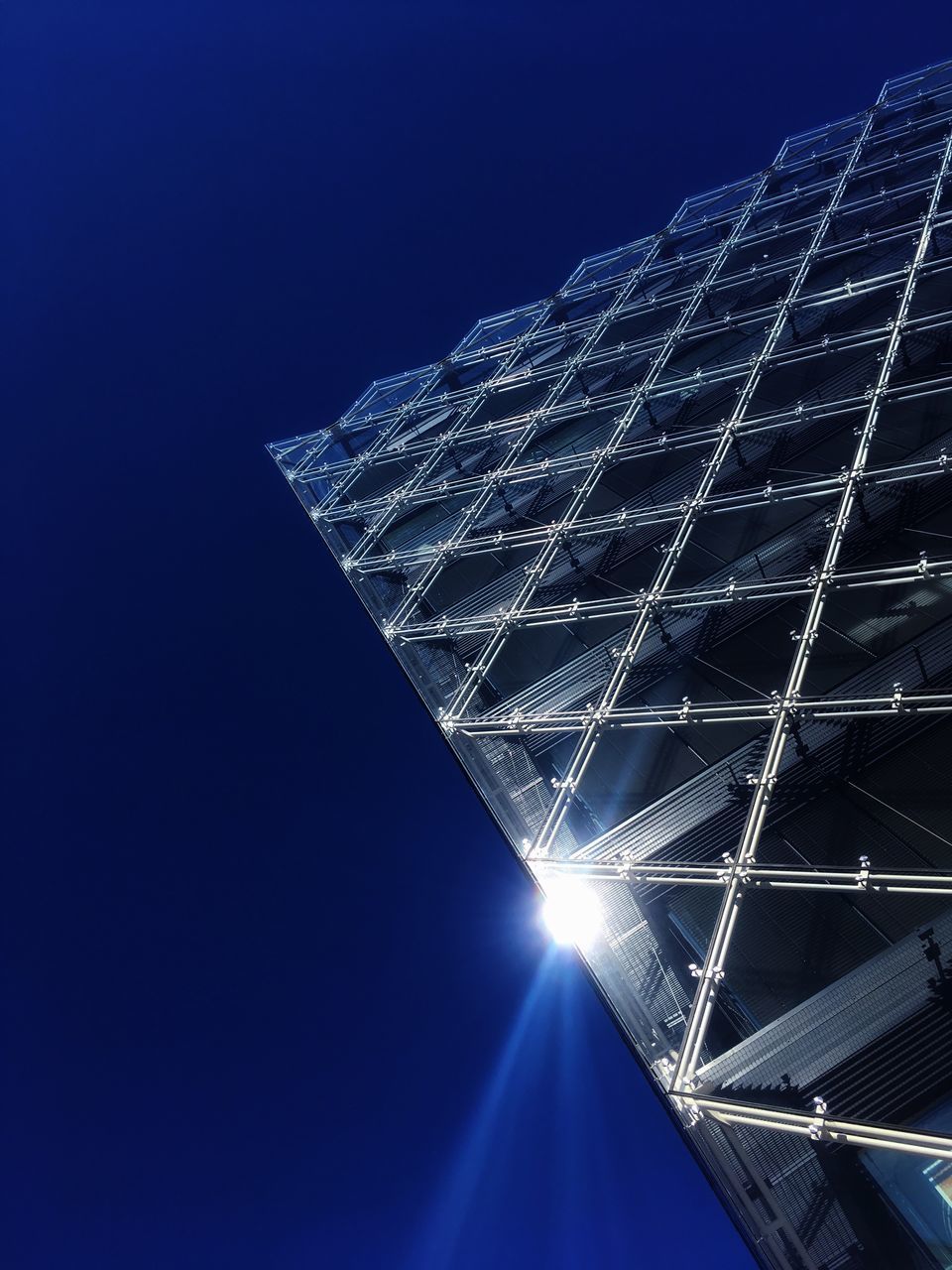 LOW ANGLE VIEW OF ILLUMINATED SKYSCRAPER AGAINST CLEAR BLUE SKY