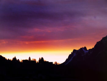 Silhouette landscape against dramatic sky during sunset