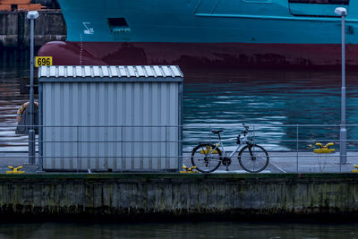 Bicycle parked on bridge against boat