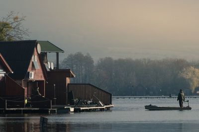 Houses by lake against sky during winter