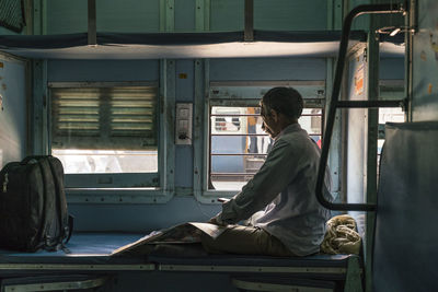 Rear view of man sitting in room