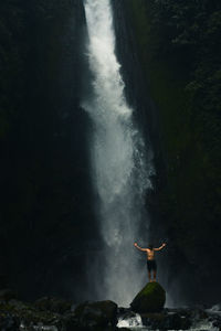 Rear view of man standing against waterfall