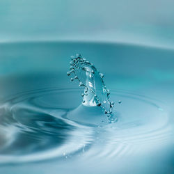 Close-up of drop falling on blue water