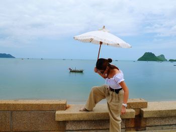 Woman sitting in sea against sky