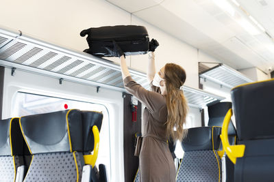 Woman holding umbrella while standing in bus