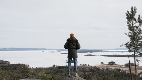 Man standing on a high rock enjoying the beautiful ocean view