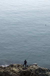 High angle view of person fishing while standing at beach against clear sky during sunny day