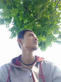 Portrait of young man looking away against plants