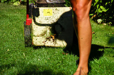 Low section of woman with lawn mower on field