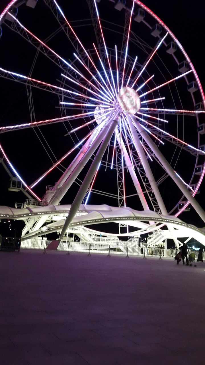 arts culture and entertainment, ferris wheel, night, illuminated, amusement park ride, amusement park, sky, low angle view, built structure, architecture, outdoors, circle, no people, incidental people, building exterior, motion, multi colored, clear sky, long exposure, travel destinations