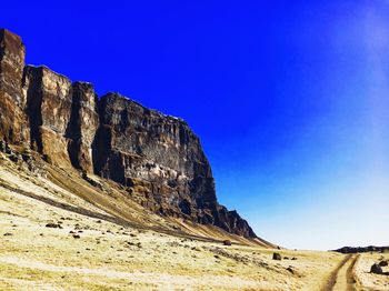 Low angle view of rock formations against clear blue sky