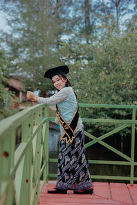 Portrait of smiling young woman standing on footbridge