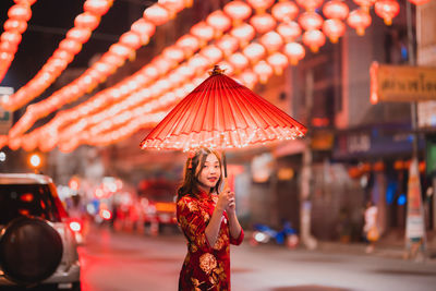 Portrait of woman with red umbrella standing on street