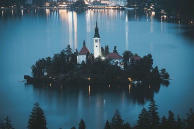 Panoramic view of illuminated buildings by lake against sky