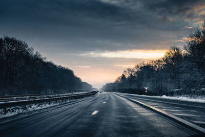 Road amidst trees against sky during sunset