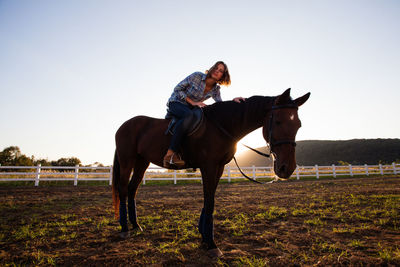 Horse riding horses in ranch against sky