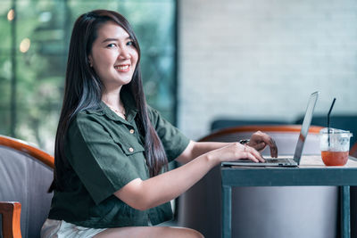 Portrait of young woman using mobile phone while sitting at home