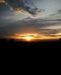 Silhouette landscape against dramatic sky during sunset