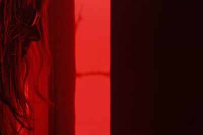 Close-up of woman against red curtain at home