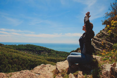 Statue of man sitting by sea against sky