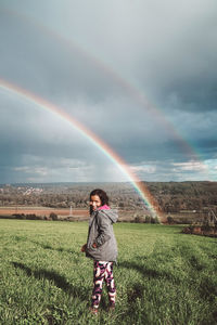 Rear view of woman walking on field against sky